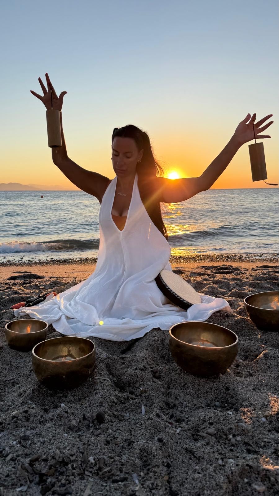 Gem — sound healing practitioner with arms raised at golden hour sunset
