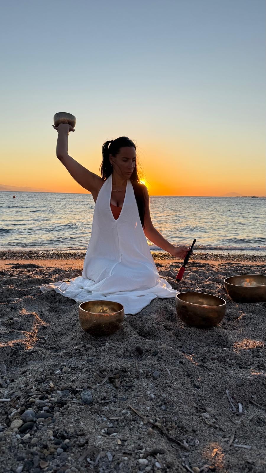 Gem holding a singing bowl aloft against a golden sunset sky