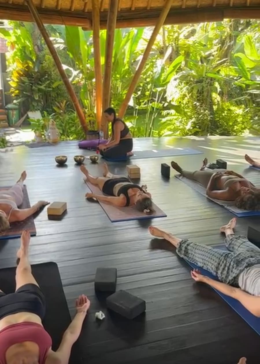 Guests resting on mats during Gem's sound bath at a jungle yoga pavilion